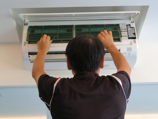Aircon technician removing filters from a home air conditioner