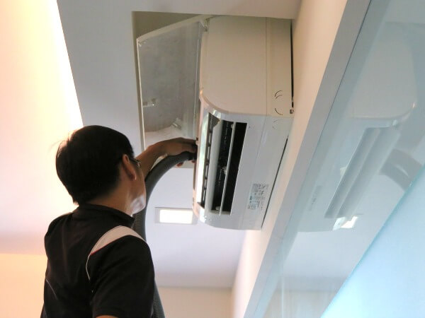 Aircon technician vacuum clean top center part of air conditioner fan coil
