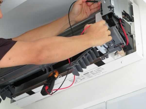 Aircon Repair Specialist taking voltage measurement on air conditioner unit