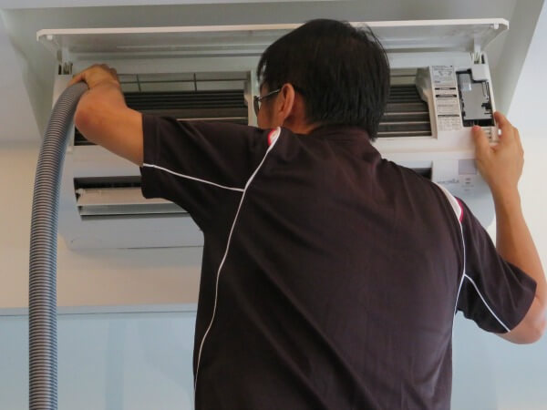 Aircon technician vacuum clean the top left part of the air conditioner fan coil