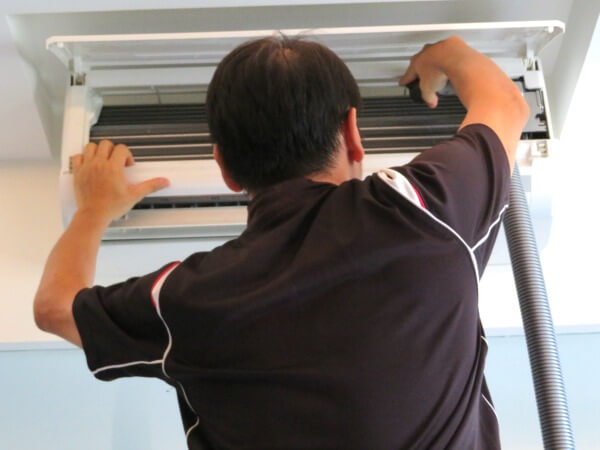 Aircon technician vacuum clean the top right part of the air conditioner fan coil