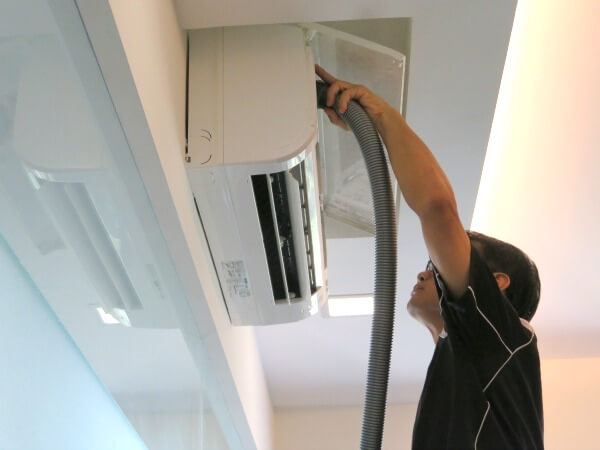 Aircon technician vacuum clean the center left part of air conditioner fan coil