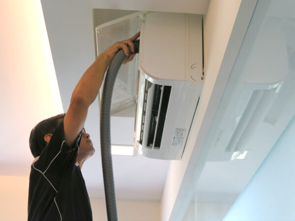 Aircon technician vacuum clean the center right part of air conditioner fan coil