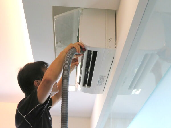 Aircon technician vacuum clean lower right part of air conditioner fan coil