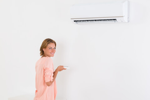 Woman smiles while turning on the air condidtioner