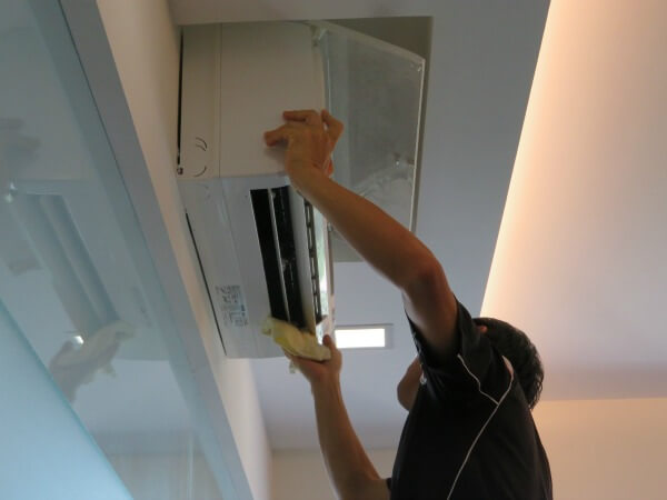 Aircon technician cleaning the lower cover of an aircon unit
